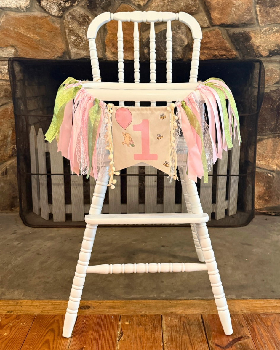 Refinished vintage Jenny Lind high chair painted white and styled with a first birthday banner