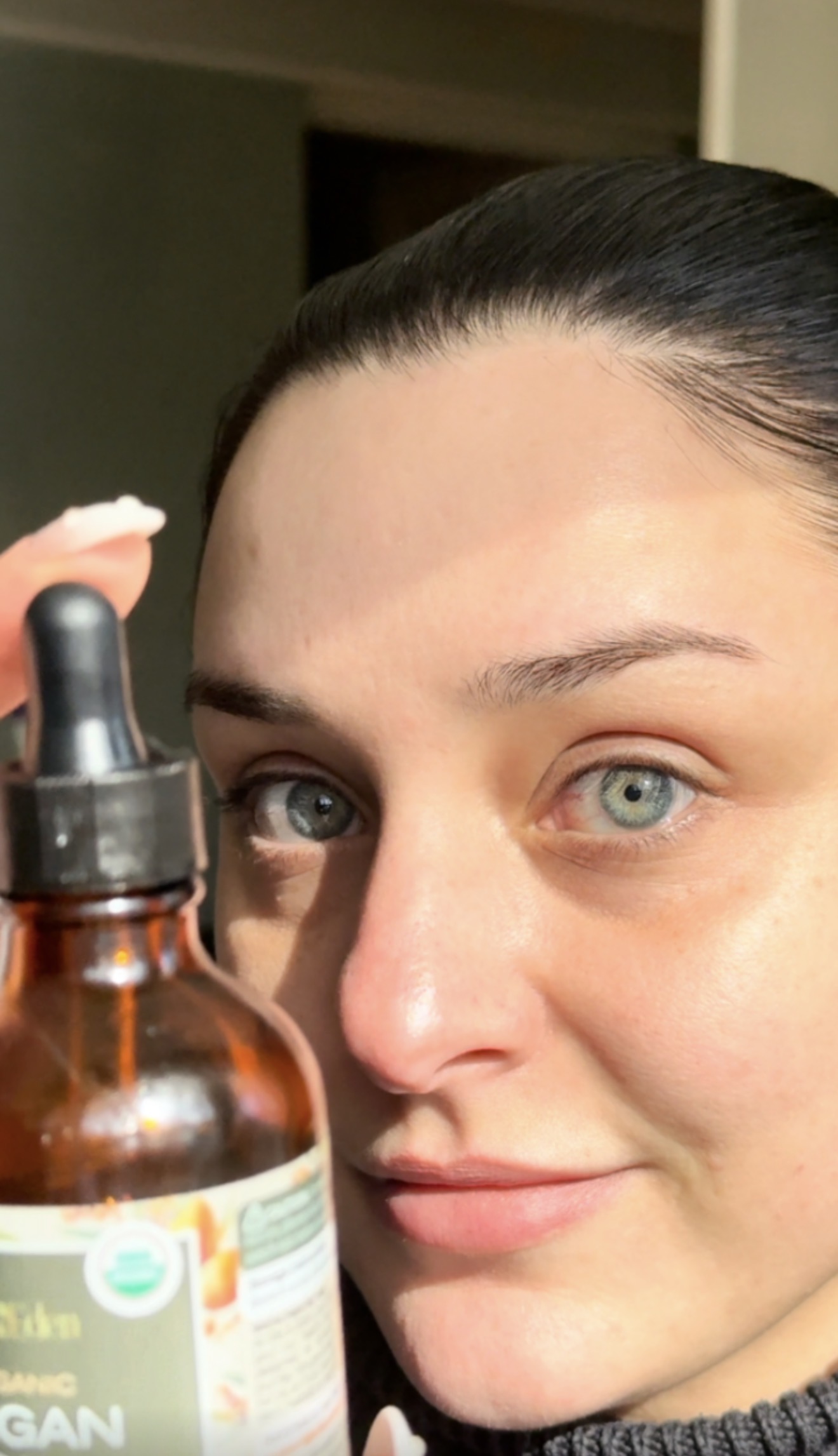 Holding a serum dropper bottle to the camera after dermaplaning